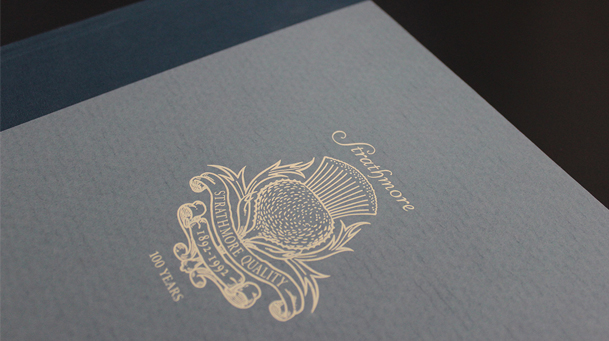 detail of a gray book cover with a gold foil stamp of the logo